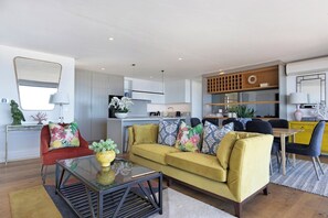 A modern living room with a yellow sofa, a glass coffee table, and a red armchair.