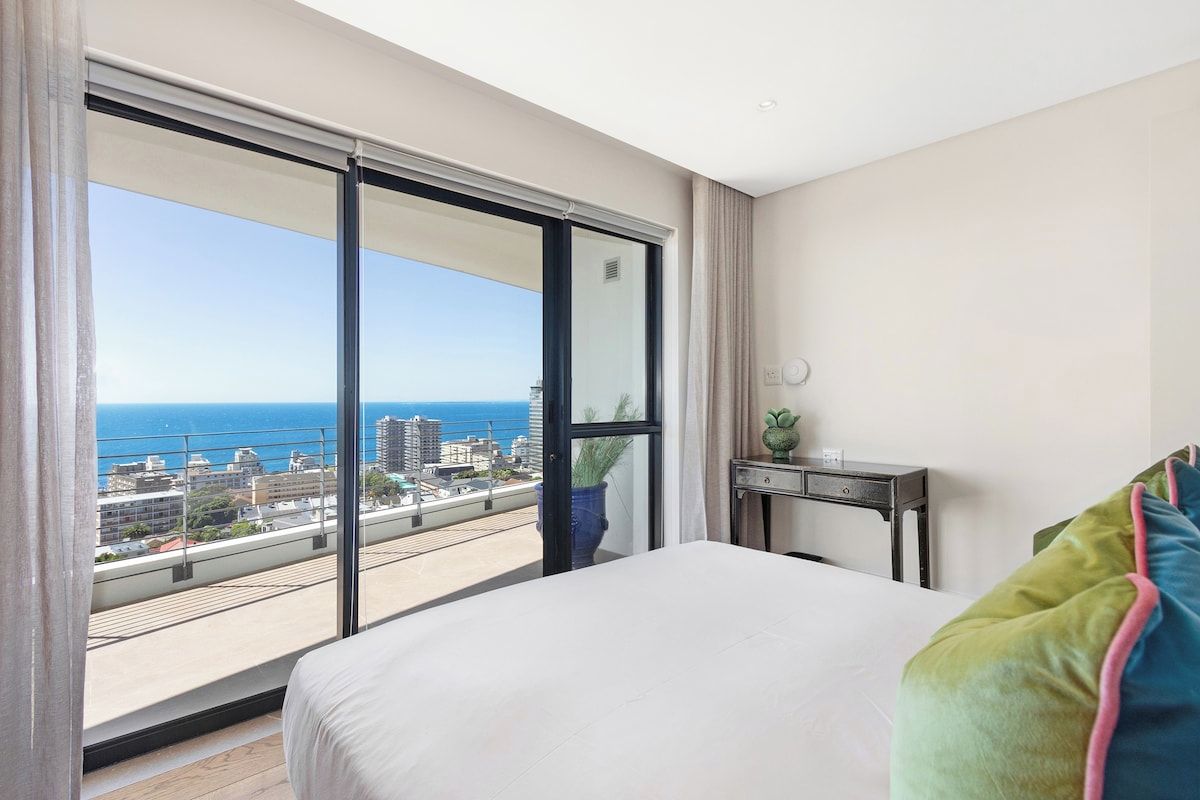 Een hotelkamer met een grote schuifpui die uitkomt op een balkon met uitzicht op de stad.
