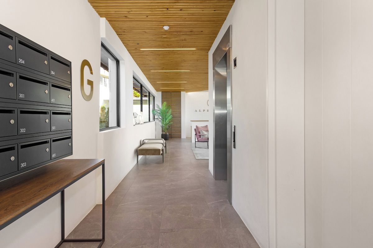 A modern hallway with lockers, a bench, and a staircase.