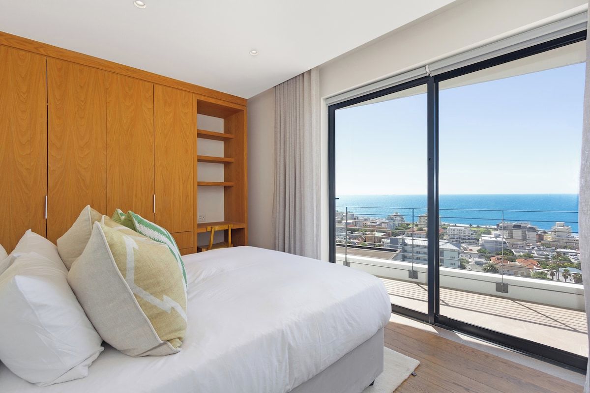 Een slaapkamer met een groot bed, een houten garderobe en uitzicht op zee.