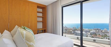 Un dormitorio con una cama grande, un armario de madera y vistas al mar.