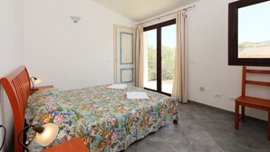 A bedroom with a bed, a desk, a chair, a lamp, and a window with a view of the outdoors. - Beautiful apartment for 4 guests with terrace (Valledoria)