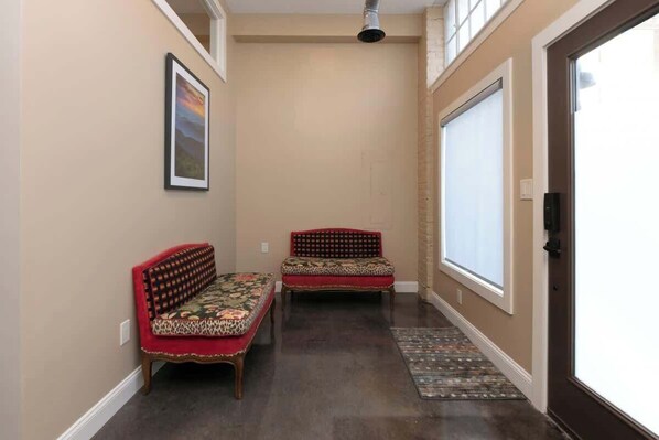 A hallway with two sofas, a patterned rug, and a door with a window. - Stay Roanoke | Bright modern loft for adventurers (Roanoke)