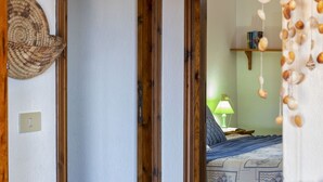 Un dormitorio con cama, mesita de noche, lámpara y estante en la pared.