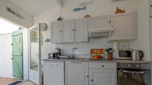 A compact kitchen with white cabinets, a built-in microwave, a coffee maker, and a small refrigerator. - Beautiful  villa for 4 guests with A/C, WIFI, TV and terrace (Le Grau-du-roi)