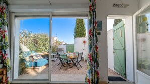 A patio area with a table and chairs, a small pool, and a green gate. - Beautiful  villa for 4 guests with A/C, WIFI, TV and terrace (Le Grau-du-roi)