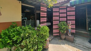 A building entrance with a covered area, a potted plant, and a statue. - PP Resort Suwintawong (Bangkok)