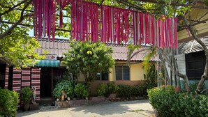 A courtyard with a paved area, potted plants, and a building with a corrugated metal roof. - PP Resort Suwintawong (Bangkok)
