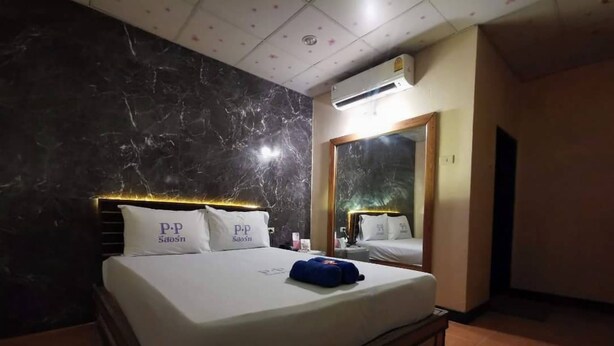 A hotel room with a marble wall, a bed with white bedding, a blue pillow, and an air conditioning unit on the ceiling. - PP Resort Suwintawong (Bangkok)