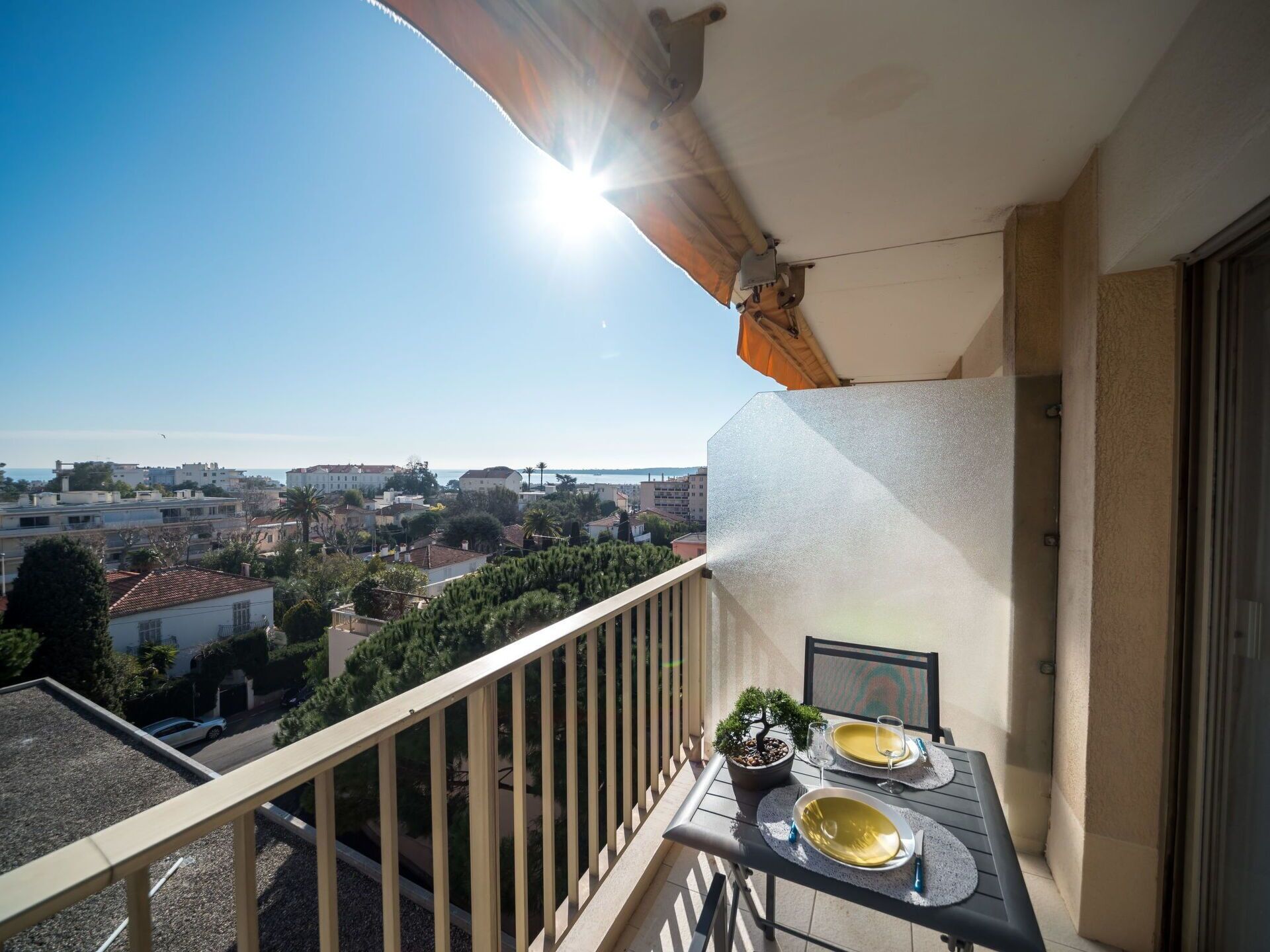 A balcony with a table set for two, overlooking a cityscape.