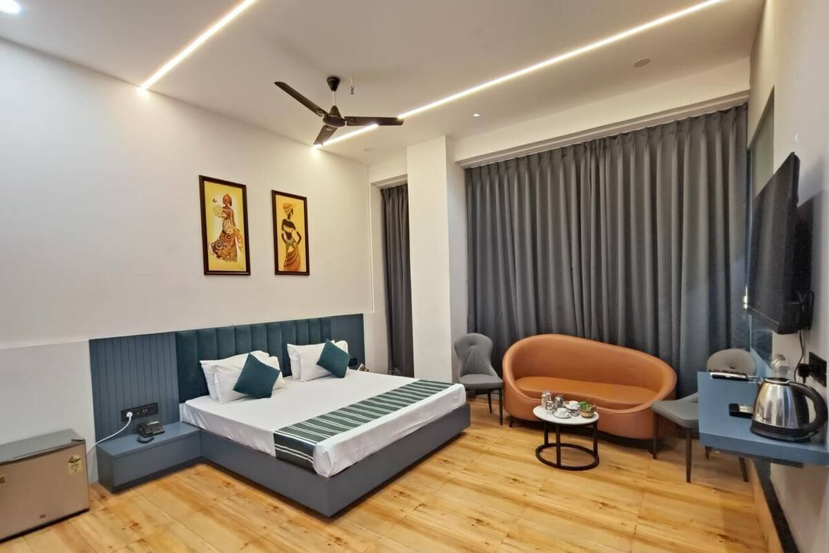 Ein modernes Hotelzimmer mit Bett, einer Couch, einem kleinen Tisch, einem Fernseher und einem Deckenventilator.