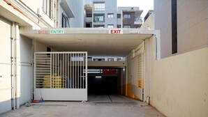 Entrada de estacionamento com placas 'ENTRY' e 'EXIT', um portão de metal e piso de concreto.