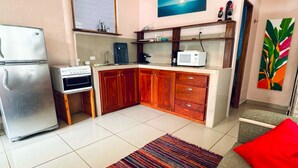 Cocina compacta con refrigerador, horno, microondas y armarios de madera.