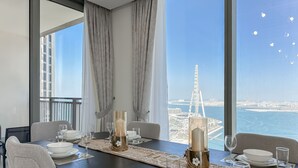 A dining area with a table set for four, a view of the cityscape, and a large window with curtains.