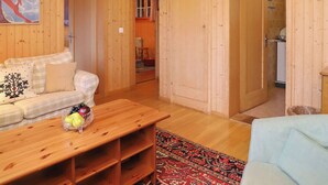 Un interno in legno con un divano, un tavolino in legno con della frutta e un tappeto decorato.