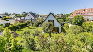 Un quartiere residenziale con case, un piccolo edificio bianco con una porta marrone e giardini curati.