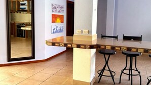 A kitchen with a tiled floor, a counter with stools, and a mirror reflecting the kitchen. - Casa midin 9, Stunning 3bd 2bth condo, GREAT location! (Puerto Carrillo)