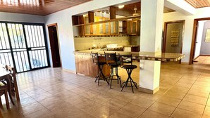 A spacious kitchen with a central island, bar stools, and wooden cabinets. - Casa midin 9, Stunning 3bd 2bth condo, GREAT location! (Puerto Carrillo)