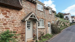 A stone cottage with a traditional design, featuring a small porch and a single door. - Stag Cottage (Minehead)