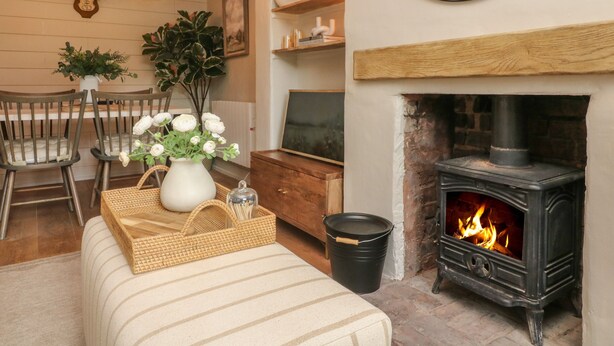 A cozy room with a fireplace, wooden furniture, and hanging lights. - Stag Cottage (Minehead)