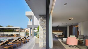 A modern interior with a pool area, lounge chairs, and a dining space. - Walking distance to Beach, Heated Pool & Rooftop Hot Tub! (Rethymno)