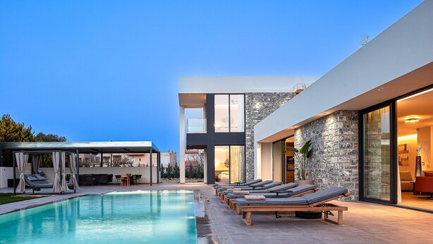 A modern pool area with lounge chairs and a covered seating area. - Walking distance to Beach, Heated Pool & Rooftop Hot Tub! (Rethymno)