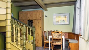 Un escalier avec des balustrades en bois, un coin repas avec des chaises et une table en bois, et un tableau encadré au mur.