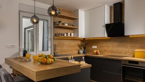 A modern kitchen with a wooden island, black cabinets, and a built-in oven. - Seaview villa Deep Green in Maslenica (Maslenica)