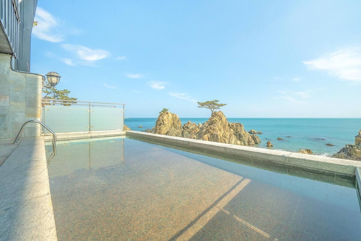 Ein Pool mit Blick auf das Meer und Felsformationen.