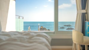 A bedroom with a view of the sea through a window, a bed, and a chair. - Gyeongju Blue21 Poolvilla Pension (Gyeongju)