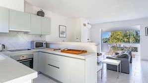 Une cuisine moderne avec des meubles blancs, un four à micro-ondes et un coin repas comprenant une table et des chaises.