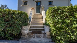 Un bâtiment à deux étages, doté d’un toit recouvert de tuiles, d’une entrée centrale avec une porte et d’un escalier menant à l’entrée.