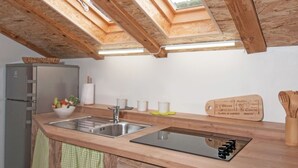 Uma cozinha com claraboia, vigas de madeira, uma pia de aço inoxidável e uma tábua de corte de madeira com texto.