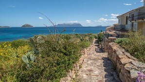 A stone pathway leading to a building with a balcony overlooking a coastal view. - Beautiful apartment for 5 people with WIFI, A/C, TV and terrace (Regia Dogana)