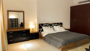 Une chambre à coucher comprenant un lit, une table de chevet, une commode, un miroir et une armoire.