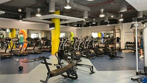 Une salle de sport équipée de tapis de course, de vélos elliptiques et de matériel de musculation.