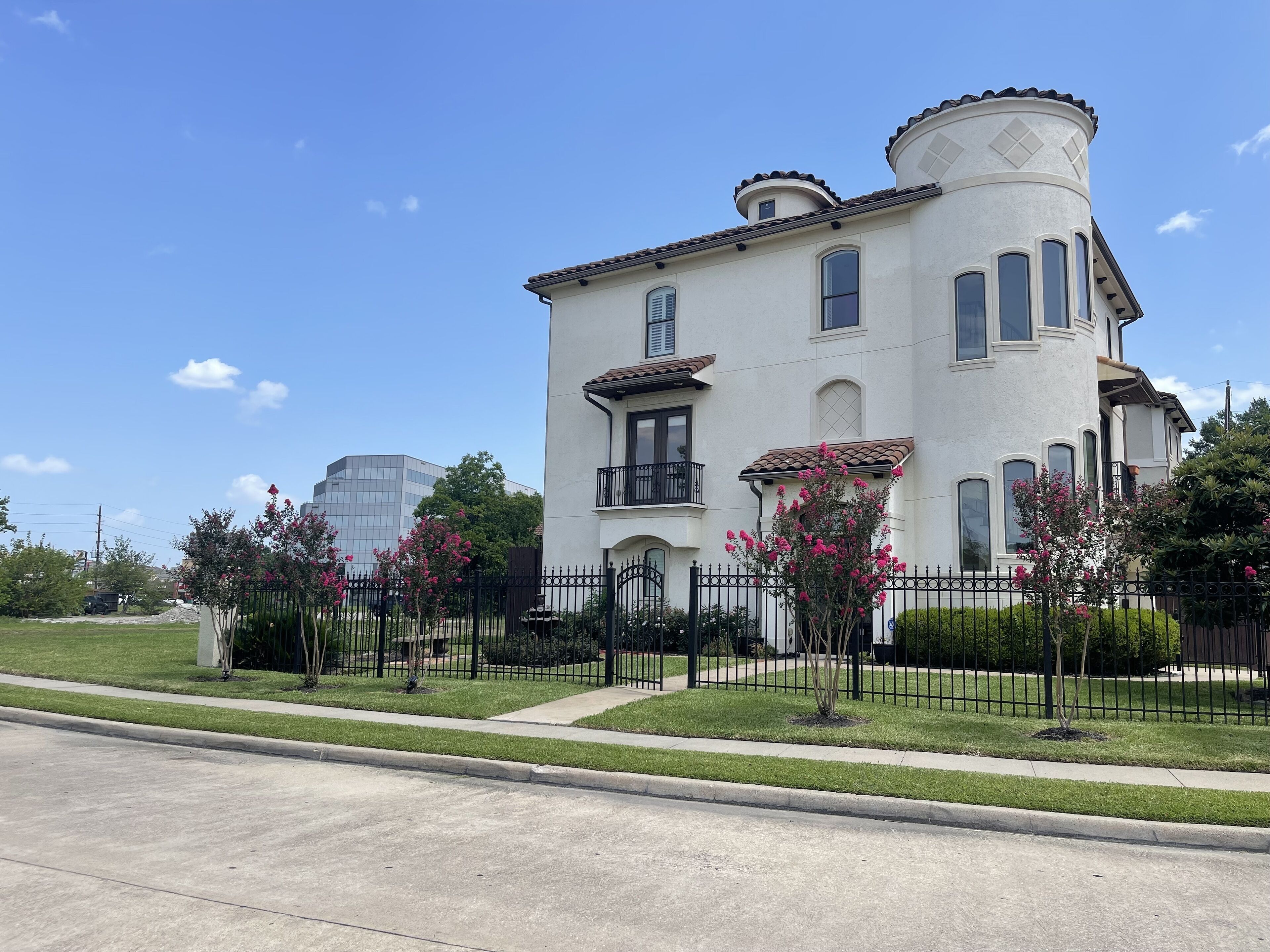 A large, two-story house with a white exterior, a balcony, and a round tower-like structure on the roof.