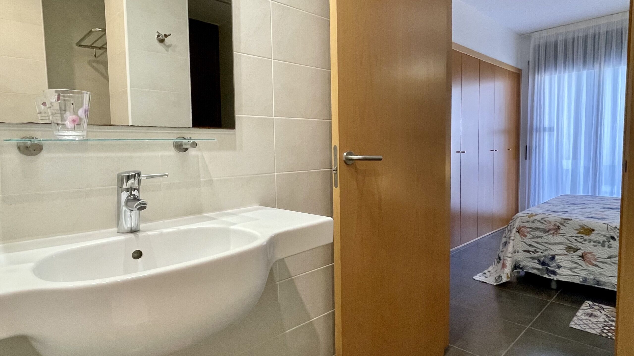 Ein Badezimmer mit Waschbecken, Spiegel und einer Glasablage.