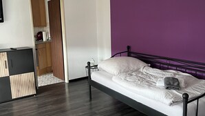 A bedroom with a bed, a wardrobe, and a bathroom visible through an open door. - Red Dot Apartments (Kamen)