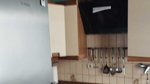 A compact kitchen with a refrigerator, a sink, and a stove. - Red Dot Apartments (Kamen)