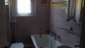 A bathroom with a toilet, bathtub, and sink. - Red Dot Apartments (Kamen)