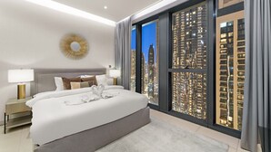 A modern hotel room with a large bed, a city view, and a sunburst mirror on the wall. - WORLD CLASS | 2BR | Downtown View (Downtown)