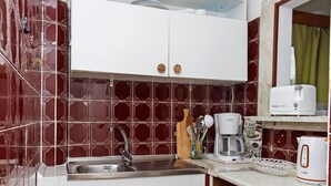 A compact kitchen with a sink, a Bosch coffee maker, a toaster, and a gas stove.