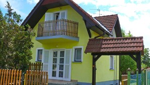 A two-story house with a balcony, a wooden fence, and a small porch.