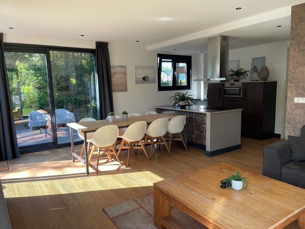 Una cocina moderna con una isla central, comedor con sillas y un sofá.