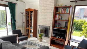 A living room with a sofa, armchairs, a bookshelf, a TV, and a fireplace. - 3 bedroom accommodation in Julianadorp aan Zee (Julianadorp aan Zee)