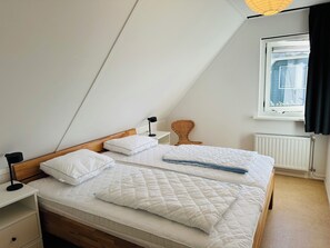 Un dormitorio con dos camas, una ventana con vistas, un radiador y una silla.