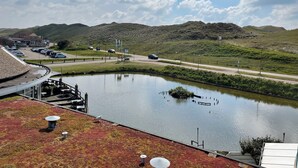 Un hotel frente al lago con vistas al lago, un área de estacionamiento y una carretera con vehículos.