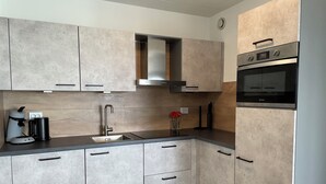 Una cocina moderna con armarios grises, un lavamanos de acero inoxidable y un horno empotrado.