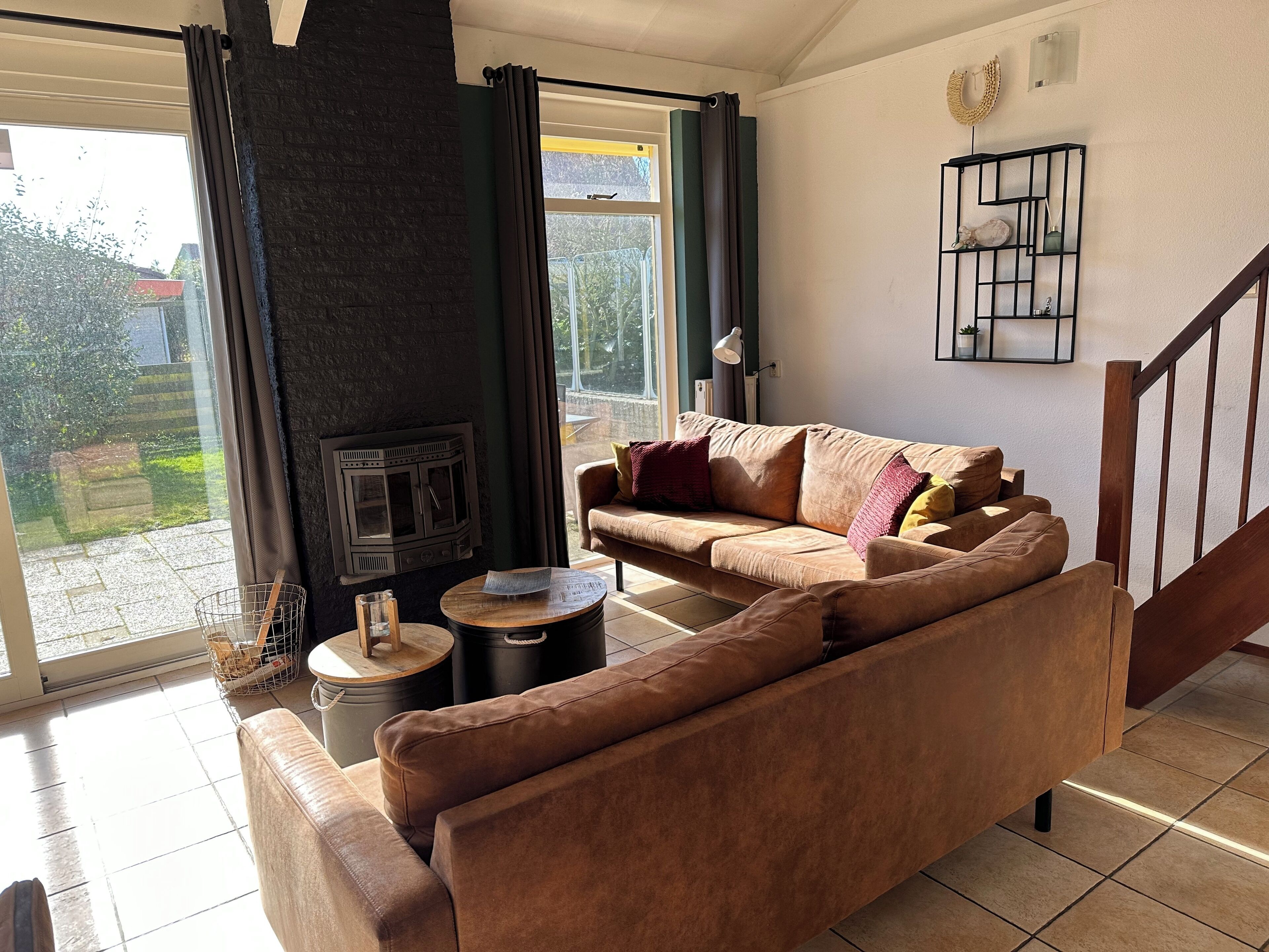 Una sala acogedora con un sofá marrón, una chimenea, una mesita redonda y una escalera.